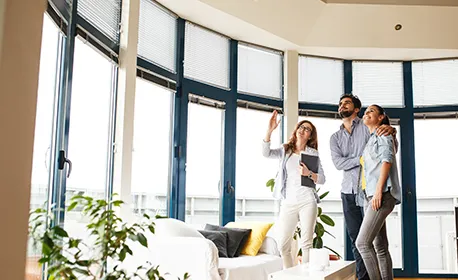 A realtor showing a couple a home with large windows, highlighting the benefits of expert realtor services for informed decision-making.